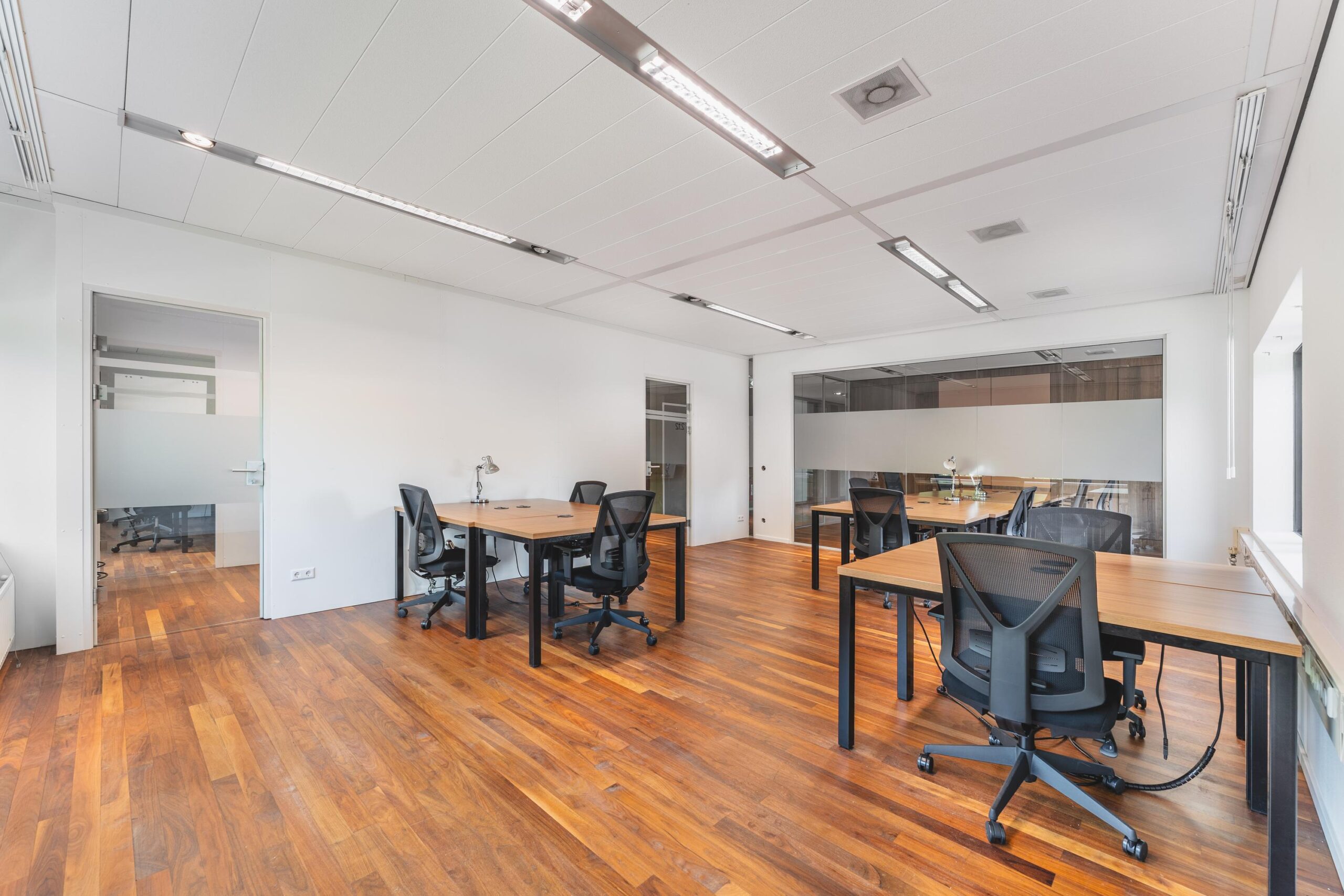 Lichte, moderne kantoorruimte aan de Prof. W.H. Keesomlaan met houten vloer en meerdere bureaus met bureaustoelen.